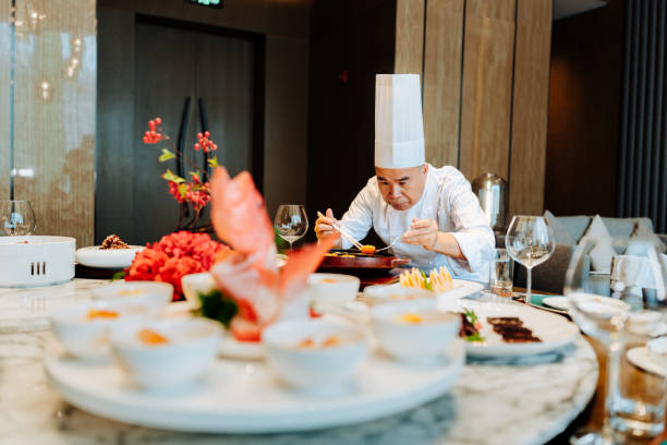 istock Asian senior chef serving meal at table a luxurious private room. 2193214239