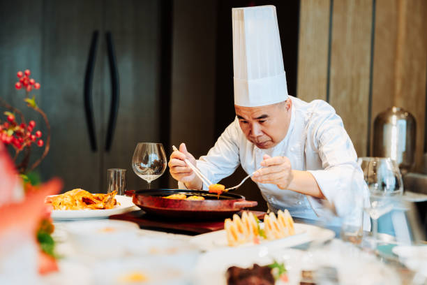 istock Asian senior chef serving meal at table a luxurious private room. 2193214253