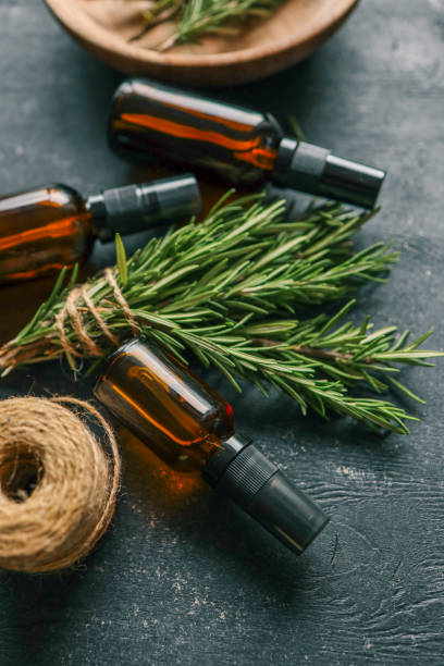 istock Amber glass spray bottle with a black cap placed on a dark rustic surface, surrounded by rosemary sprigs and natural decor elements. Concept of natural, eco-friendly cosmetics or aromatherapy products 2193215645