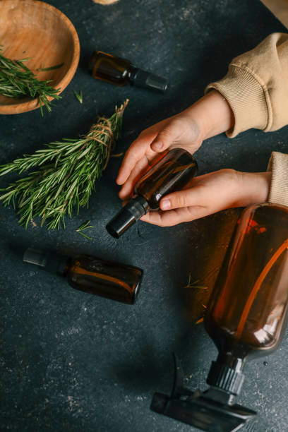 istock Amber glass spray bottle with a black cap placed on a dark rustic surface, surrounded by rosemary sprigs and natural decor elements. Concept of natural, eco-friendly cosmetics or aromatherapy products 2193215650