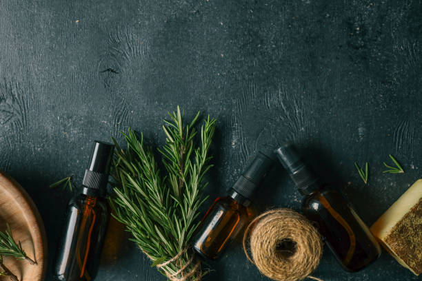 istock Amber glass spray bottle with a black cap placed on a dark rustic surface, surrounded by rosemary sprigs and natural decor elements. Concept of natural, eco-friendly cosmetics or aromatherapy products 2193215653
