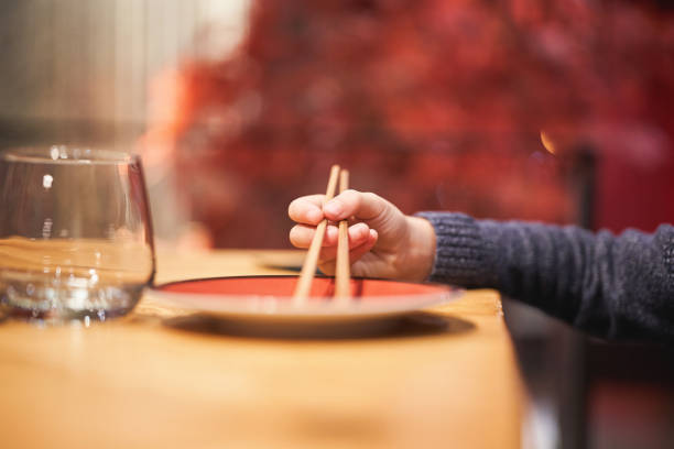 White bowl with blue pattern outside and wooden chopsticks on brown background, traditional wooden sticks for asian food.
