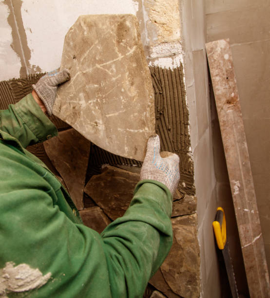 istock A man is holding a tile in his hand while working on a wall 2193217906