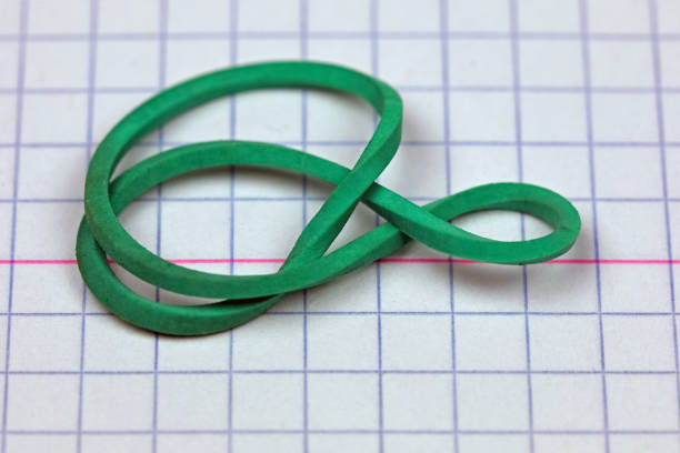 A green rubber band is lying on a piece of checkered paper.