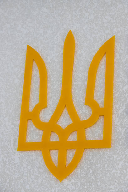 A vibrant yellow trident symbol rests on a light textured background. The emblem is outlined distinctly, showcasing intricate design details, capturing attention in the modern décor.