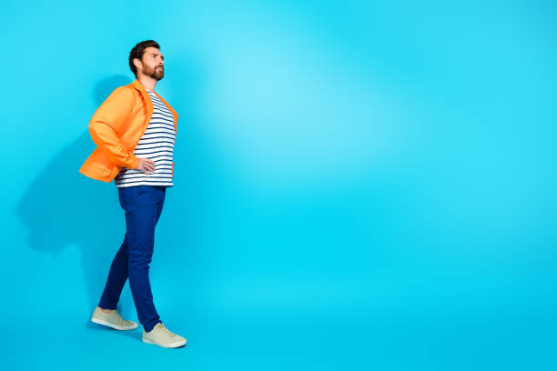 istock Young man in vibrant orange jacket posing stylishly against a bright teal background, showcasing modern fashion and charisma 2193226552