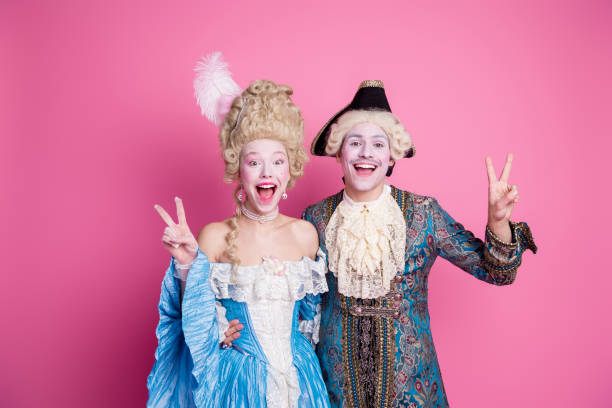 istock Two young adults in vibrant baroque costumes pose joyfully against a pink backdrop, embodying elegance and fun. 2193227497