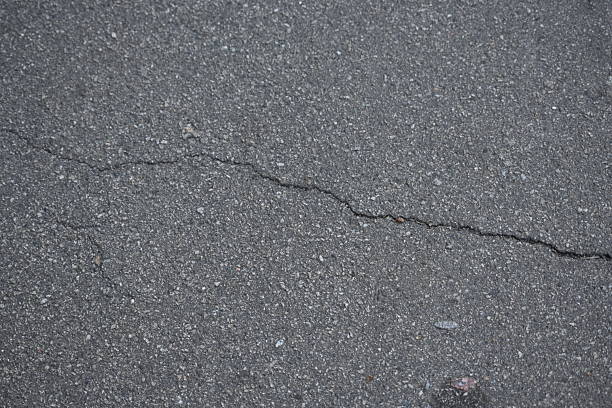 Cracks on grey asphalt close-up, old cracked asphalt close-up, old road surface bitumen