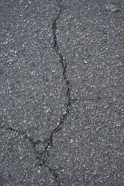 istock Cracks on grey asphalt close-up, old cracked asphalt close-up, old road surface bitumen 2193228993