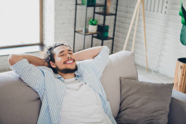 istock Joyful young man relaxing on comfortable couch in modern home interior 2193231015