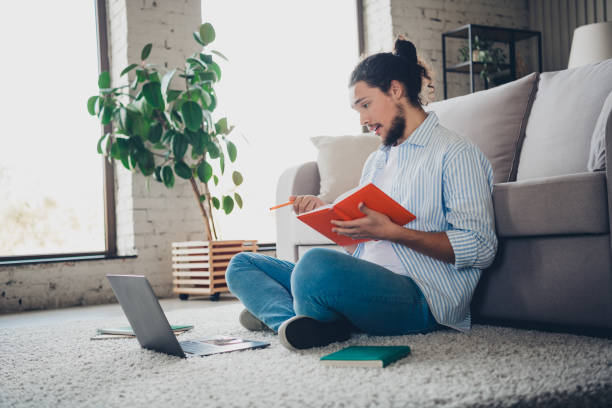 istock Young man writing notes while working with a laptop in a cozy living room 2193231032