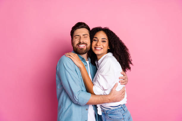 istock Happy multiethnic couple embracing and smiling against a pink background 2193231277