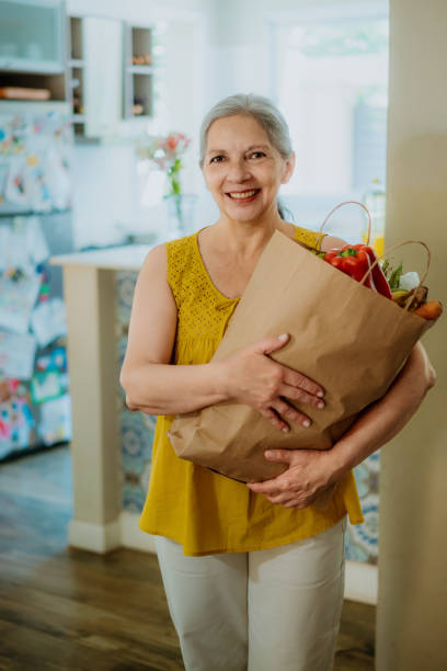 istock Smiling Woman Holding Grocery Bag in a Bright Kitchen Setting 2193231821