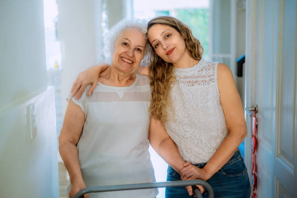 Two women, an elderly one using a walker and a younger one, share a moment of love and connection in a bright and welcoming household environment, fostering care and family bonds.