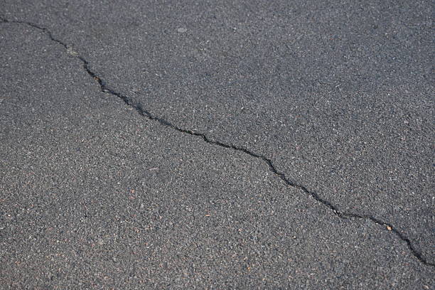 old cracked asphalt close-up, old cracked symmetrical pavement as a background, cracks on macro asphalt