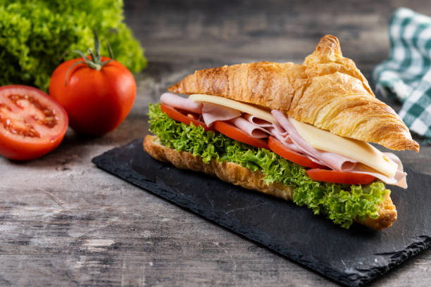 istock Croissant with ham, cheese and vegetables on wooden table 2193233840