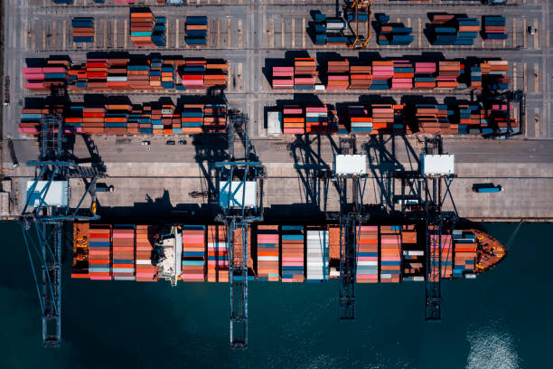 istock commercial port in deep sea load and unloading cargo from container ship import export by crane for distributing goods by trailers transport logistic  to customers and dealers, aerial top view 2193237432