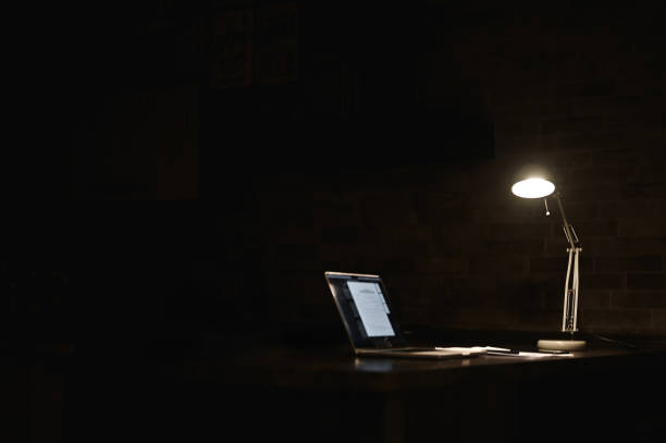 Laptop with desk lamp on black backgrounds.