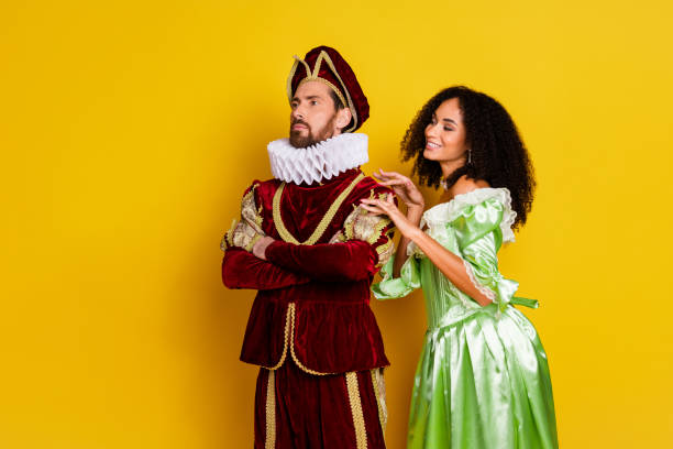 istock Elegant Couple Posing in Historical Costumes with Vibrant Yellow Background 2193242568