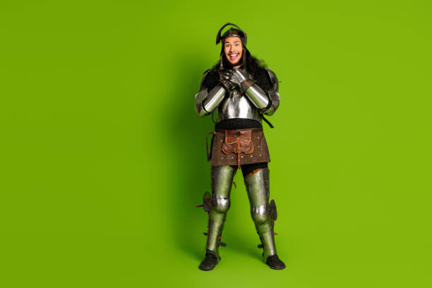 istock Man Dressed as a Knight in Armor with a Smile, Standing Against Green Background 2193243076