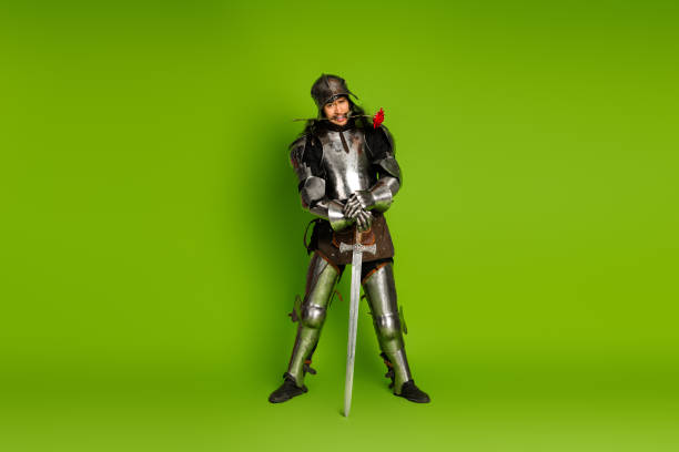 istock Medieval knight in steel armor posing with a sword on a green background 2193243105