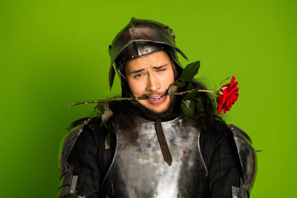 istock Humorous medieval knight with armor and rose against green background 2193243112