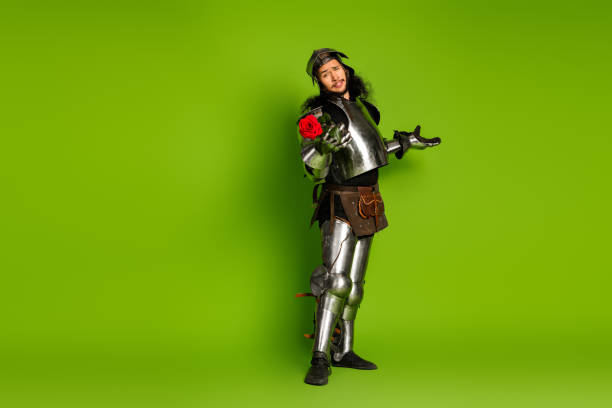 istock Medieval knight in full armor with red rose on green background expressing chivalry and romance 2193243135