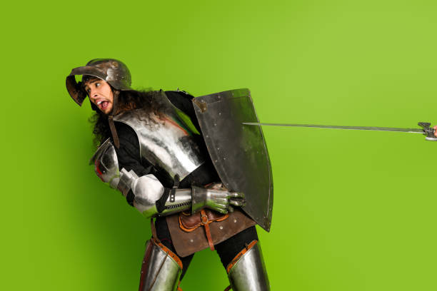 istock Funny medieval knight in armor on green background holding shield and sword, portraying a mix of history and comedy 2193243201