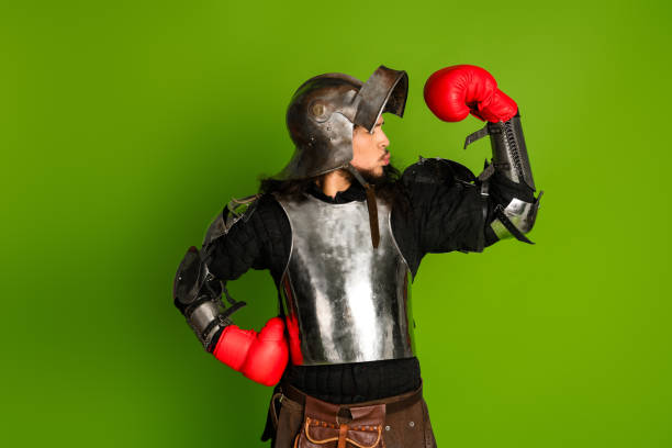 Creative medieval knight with boxing gloves posing against a vivid green background