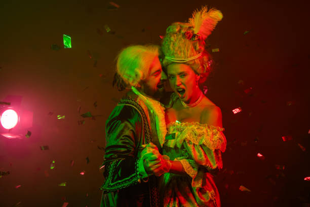 istock Young couple wearing aristocratic costumes in a dramatic light setting dancing at a themed masquerade party 2193243817