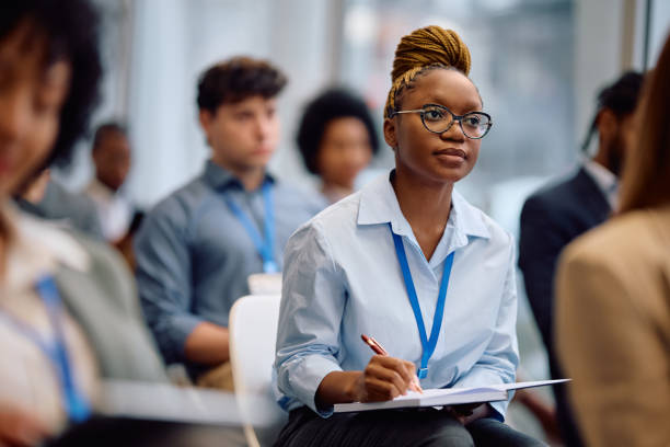 istock Black female manager writing in notebook while attending business seminar in conference hall. 2193247503