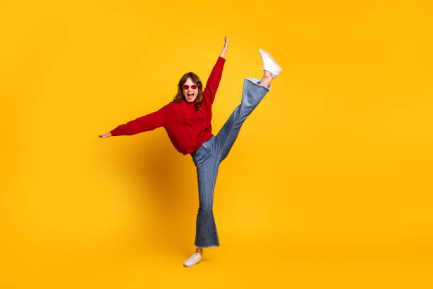 istock Cheerful young woman posing energetically in vibrant clothing against a solid yellow background 2193247566