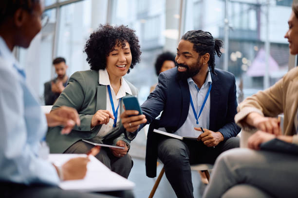 istock Happy black colleagues using cell phone during business seminar in board room. 2193247617