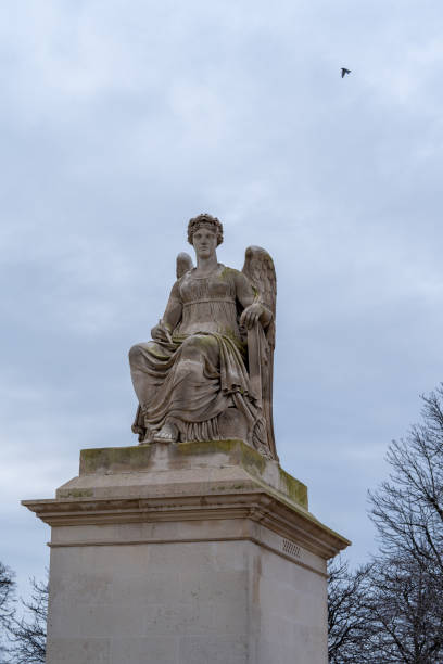 istock Statue of a winged figure seated on a pedestal under an overcast sky 2193248162