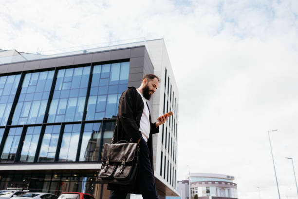 istock Businessman walking and using smartphone in urban setting 2193248387