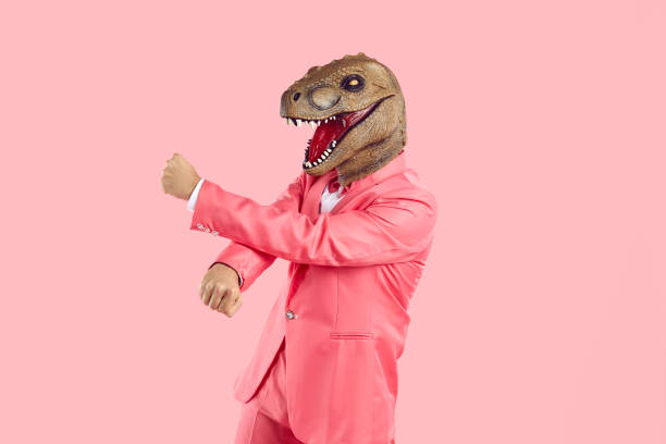 istock Funny crazy man with mask lizard or dinosaur head dancing isolated on pink background. 2193248683