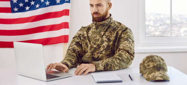 istock Young soldier who serves in US army sitting in office and working on laptop computer 2193249169