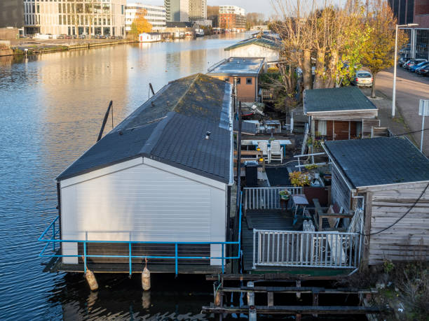 Amsterdam, Netherlands - Nov 29, 2019: Houseboat along the Duivenrechtsevaart (river). Apartment flat with a kitchen, living room, one or more bedrooms, bathroom and usually a small terrace.