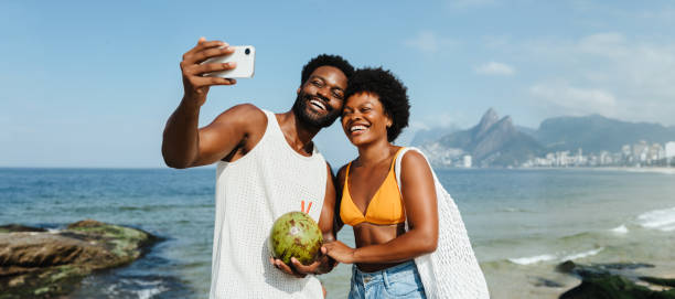 Happy tourists taking a selfie on Ipanema Beach during vacation