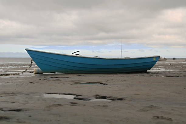 Blue Rowboat Beached And Resting On The Sand During Low Tide