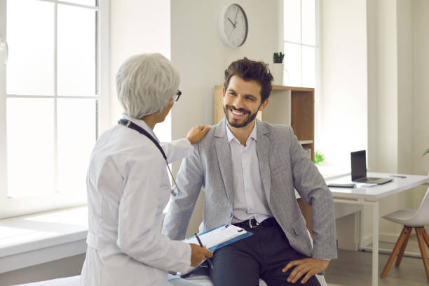 Happy young man listening to doctor during consultation in modern clinic or hospital stock photo