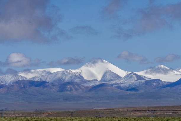 Grasslands, snow-capped mountains and blue sky and white clouds on the plateau