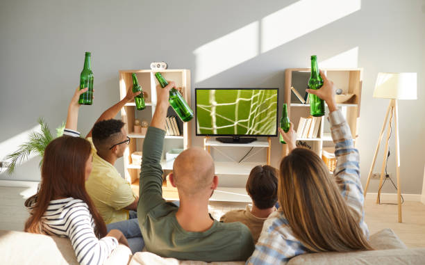 istock Young people relax at home with beer watching football 2193262485