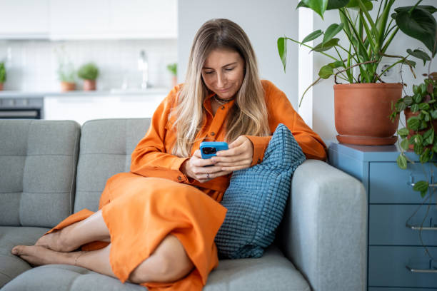 istock Positive woman resting on couch at home, absorbed in smartphone, enjoying time. Web feed connection 2193263809