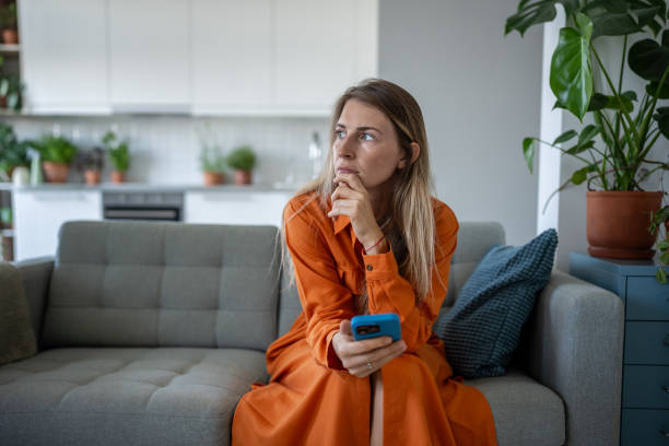 istock Overthinking upset woman with smartphone sit on sofa, wait for call, message alone. Stress, crisis 2193263856