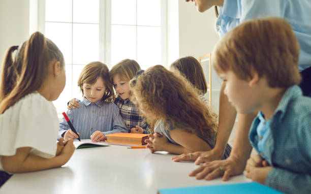 istock School children learning, writing, communicating and helping each other in classroom 2193263887