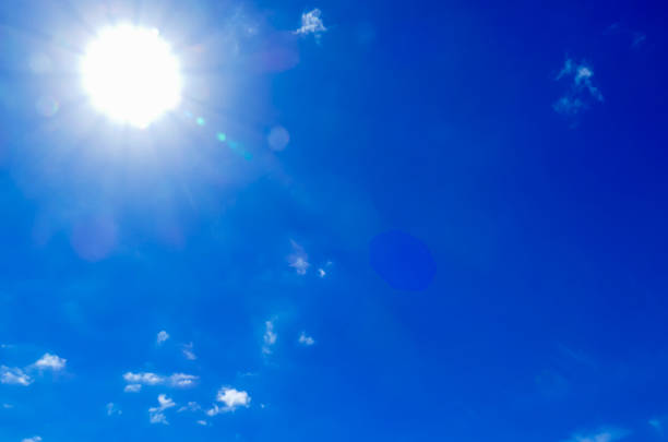 The sun is shining brightly in the sky, casting a warm glow on the blue clouds. Concept of happiness and positivity, as the bright blue sky and the sun's rays create a cheerful atmosphere
