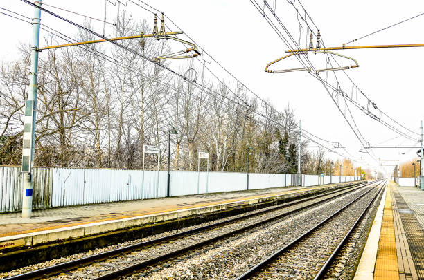 A train track with a white fence in the background. The fence is empty and the train tracks are empty