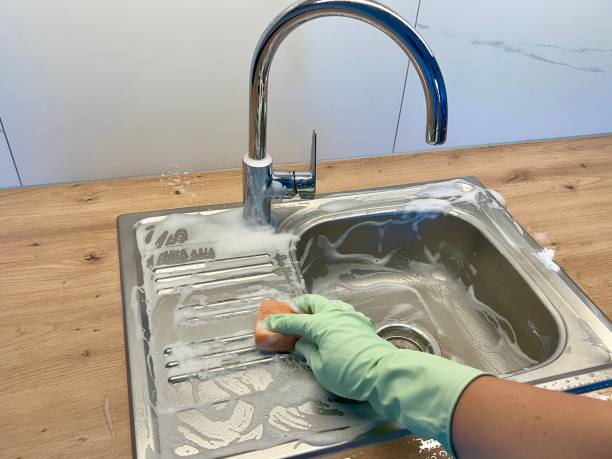 istock A hand in a rubber glove washes the kitchen sink with a sponge 2193267257