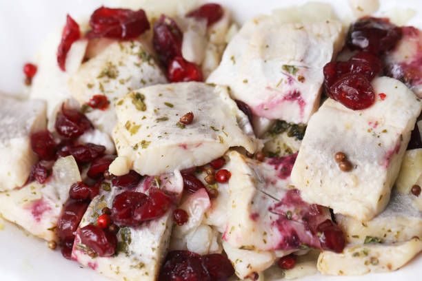 Herrings sprinkle with spices. Pickled fish background.